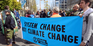 Junge Menschen halten ein Transparent auf dem steht: "System change not climate change"