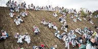 Demonstranten in weißen Maleranzügen rutschen eine Berg runter
