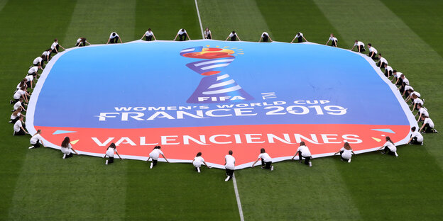 Auf dem Fußballfeld halten Spielerinnen ein riesiges Banner der Fifa
