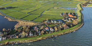 Kleines Dorf am Rand eines hohen Deichs