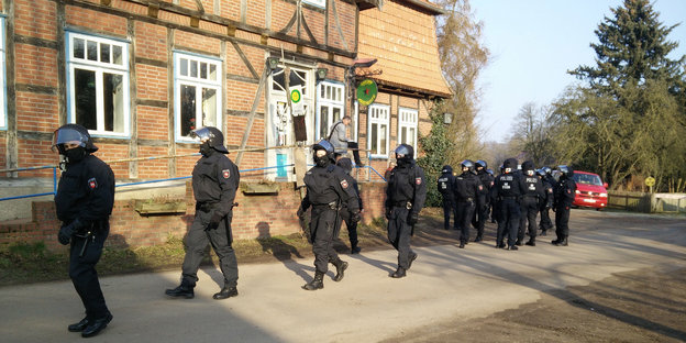 Polizisten in Kampfmontur versammeln sich vor einem Gasthof.