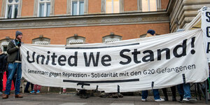 Demonstranten stehen mit einem Transparent mit der Aufschrift "United we stand" vor dem Landgericht in Hamburg