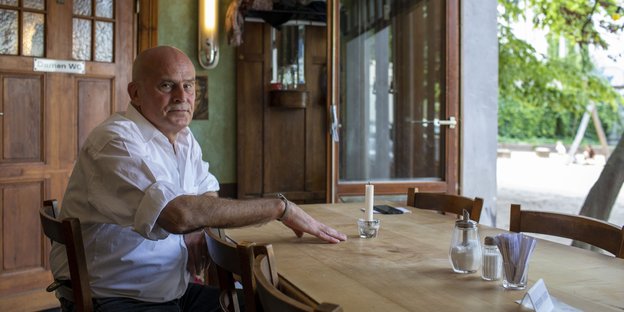 Der Betreiber der Bar Alois S., Lothar Heer sitzt an einem Tisch in seiner Bar mit Blick auf den daneben liegenden Spielplatz