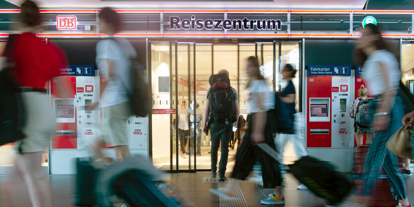 Passanten mit Koffern gehen an einem Reisezentrum der Deutschen Bahn vorbei