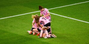 Frauen in rosa Trikots jubeln und umarmen sich