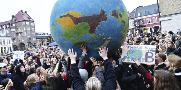 Schüler nehmen an einer «Fridays for Future»-Klimademonstration teil und schubsen einen übergroßen Erdball umher