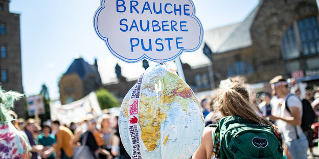 Protestmarsch in Aachen: Demonstranten halten ein Schild mit "Brauche Saubere Puste" hochsnten mit einemZwei PolizistInnnen stehen vor einem Abraumbagger im Braunkohletagebau Garzweiler