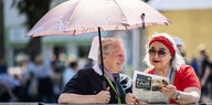 Eine Diakonistin und ihre Freundin schützen sich mit einem Schirm vor der Sonne