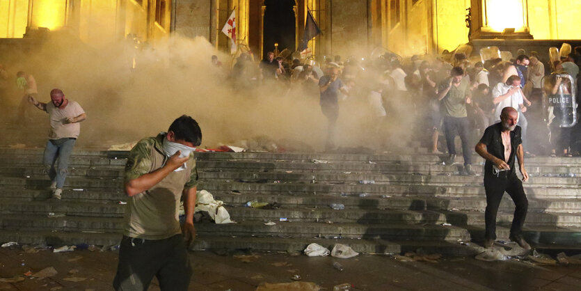 In der Nacht fliehen vor dem Parlament in Tbilisi Menschen vor Tränengas.