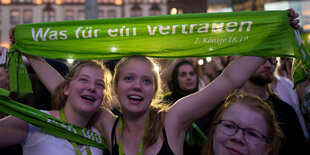 Drei junge Frauen beim Kirchentag mit einem Schal in der Hand