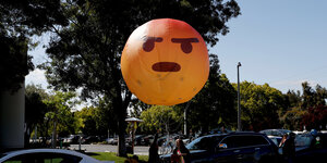 Ein großer Luftballon schwebt über dem Boden mit einem zornigen Gesicht
