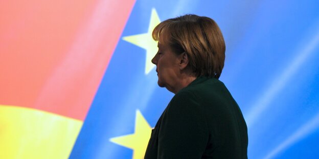 Angela Merkel geht an einer Europa-Flagge vorbei