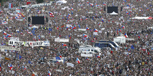 Eine Menschenmenge, die das Bild vollständig ausfüllt, manche Menschen halten Polen-Flaggen