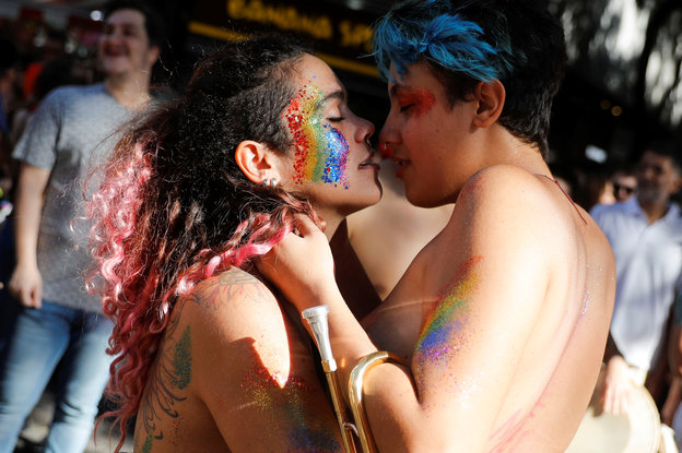 Ein lesbisches Paar mit jeweils nackten Oberkörpern und bemalten Gesichtern küsst sich