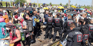 Umweltaktivisten und Polizisten stehen sich auf Bahngleisengegenüber