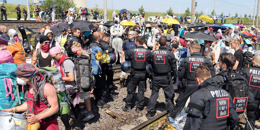 Umweltaktivisten und Polizisten stehen sich auf Bahngleisengegenüber