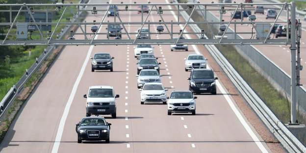 Verschiedene Pkw und Transporter fahren unter einer Mautbrücke auf der Autobahn A9 hindurch.