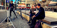 Frau im Gespräch mit Mann auf Platz in Dresden, daneben Kamerastative