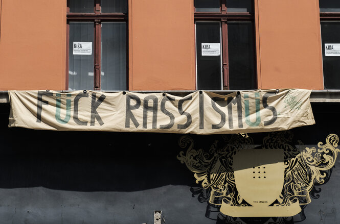 An der Hausfassade des Projektes KIgA hängt ein Banner mit dem Schriftzug Fück Rassismüs