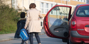 Ein Kind wird von seiner Mutter mit dem Auto zur Schule gebracht