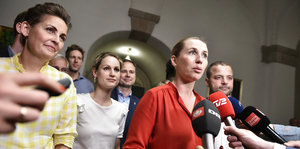 Drei Frauen und ein Mann stehen vor Mikrofonen