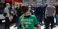 Eien frau trägt ein "Boykott Israel"-Shirt, im Hintergund mänliche Mitglieder des Jugendwiderstands