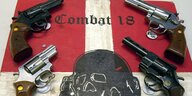 Auf rot-weißen Schild steht Combat 18, darum liegen vier Waffen