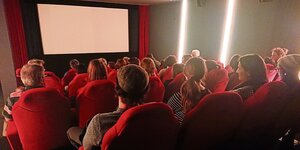 Zuschauer sitzen im Cine K in Oldenburg und schauen Richtung Leinwand. Die Leinwand ist weiß.