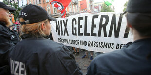 Polizisten stehen vor einem Demo-Transparent