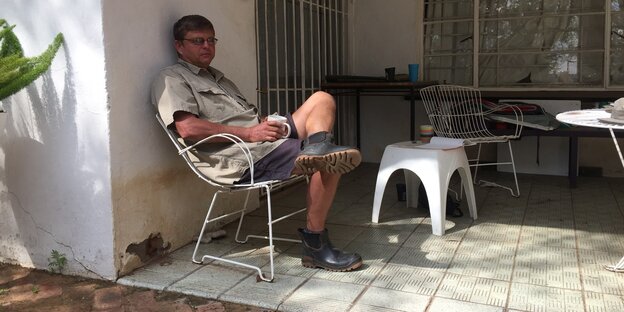 Ein trauriger Mann sitzt auf einem Gartenstuhl auf der Terasse