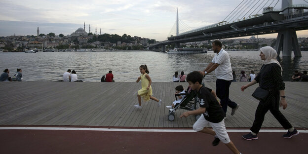 Eine Familie spaziert eine Promenade am Meer in Istanbul entlang.