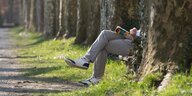 Ein lesender Mann mit einem Buch zwischen Bäumen