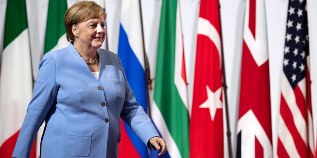 Angela Merkel läuft an Flaggen vorbei