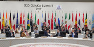 Vertreter der G20-Länder sitzen unter Länder Flaggen gemeinsam im Halbkreis