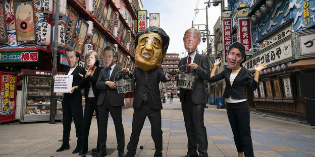 Aktivisten tragen Masken der G20-Politiker in Osaka
