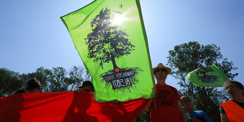 Menschen halten rote und grüne Stoffplanen hoch