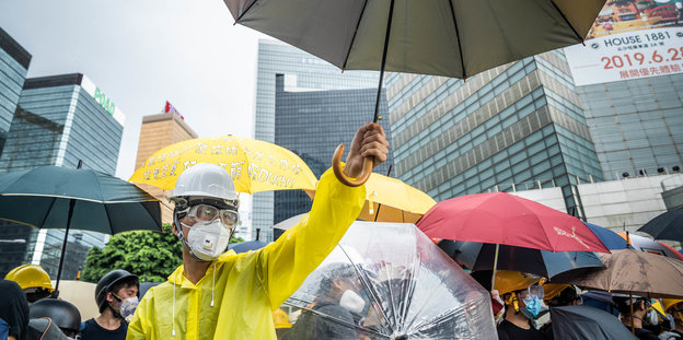 Demonstranten protestieren mit Regenschirmen auf einer Straße während der Feierlichkeiten zum 22. Jahrestag der Rückgabe der ehemaligen britischen Kronkolonie an China