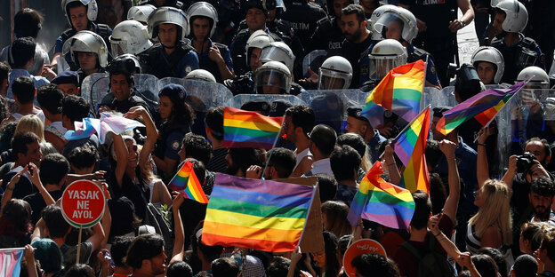 In Istanbul stehen Polizisten vor einer Menschenmenge, die Regenbogenflaggen schwenkt