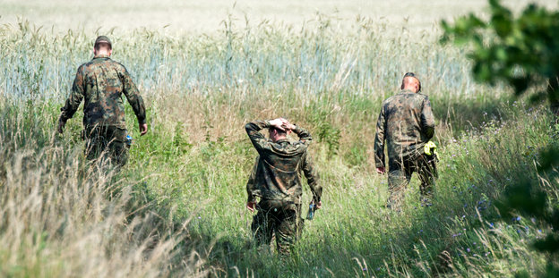 Soldaten suchen ein Feld nach Wrackteilen ab