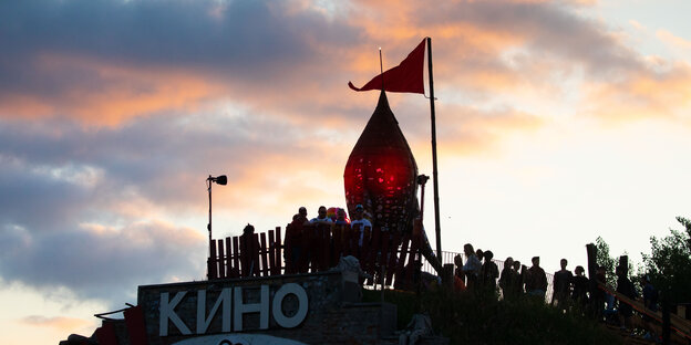 Die Fusion-Rakete und eine rote Fahne auf dem Hangar des Kinos im Sonnenuntergang