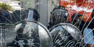 Hongkong:Polizisten hinter einer zerstörten Glasscheibe