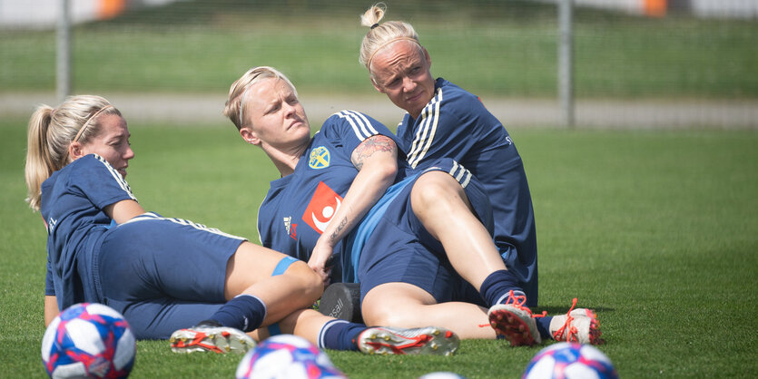 Linda Sembrant, Nilla Fischer und Caroline Seger sitzen auf einem Fußballfeld