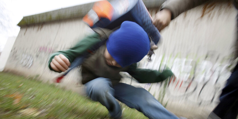 Ein Schüler drückt auf dem Schulhof eines Gymnasiums einen anderen Schüler zu Boden