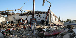 Menschen laufen über Trümmer nach einem Luftangriff auf ein Internierungslager im libyschen Tajoura