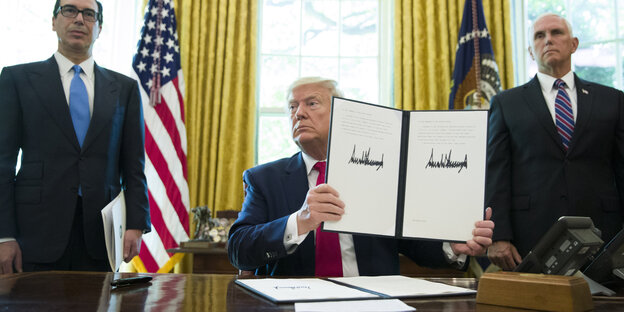 Trump hält das unterschriebene Papier hoch, auf dem Santkionen gegen Iran beschlossen wurden
