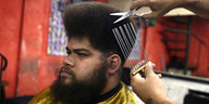 Ein Mann bekommt im glamorösen Root´s Afro Style Haarsalon eine neue Frisur