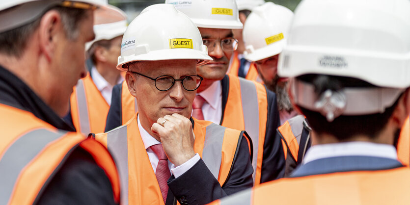 Hamburgs Erster Bürgermeister Tschentscher mit Bauhelm und Weste zwischen anderen Männern mit Bauhelm und Weste