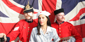 Vor Union Jack in roter Uniform die britische Punklegende Wild Billy Childish zusammen mit einer Kollegin und einem Kollegen.