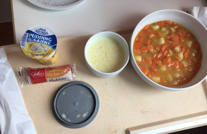 Ein Tablett mit Krankenhausessen, Möhrensuppe und Grießpudding