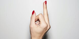 Ein Mittelfinger mit rot lackierten Nägeln